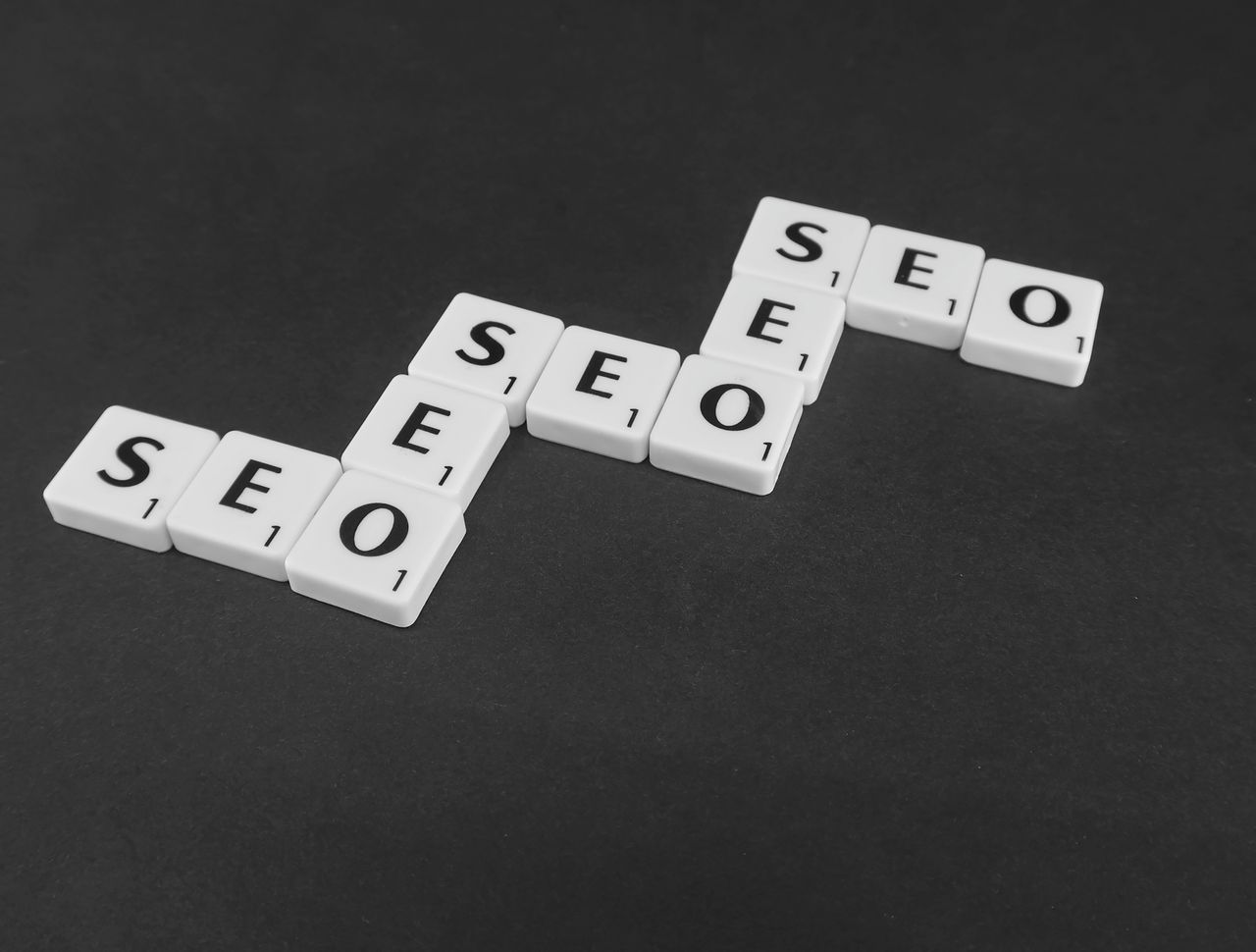 team-02 SEO spelled with Scrabble tiles on a black surface, representing search engine optimization concepts.