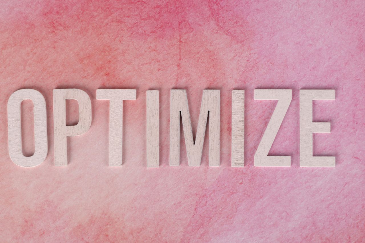 services-03 Creative display of the word OPTIMIZE on a pink textured surface.